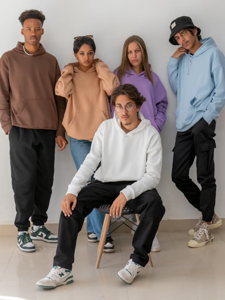 A stylish group of young adults modeling hoodies in a modern indoor setting.