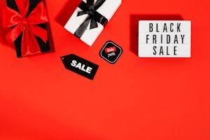Flat lay of Black Friday sale promotion with gift boxes on a red background. Ideal for shopping and marketing visuals.