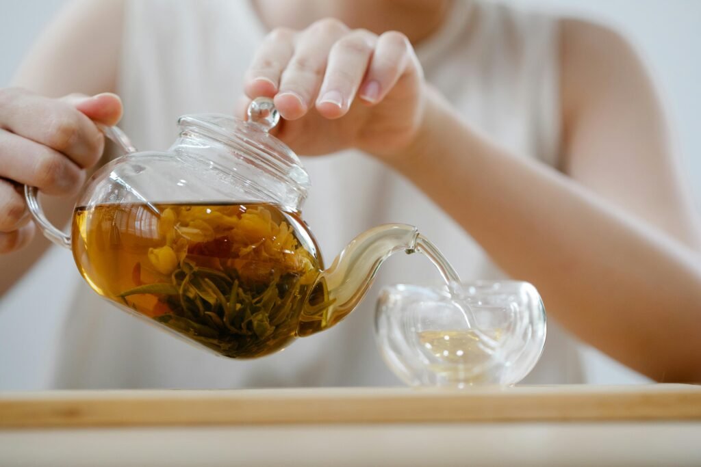 Adult woman pouring herbal tea into a cup, showcasing a cozy indoor tea ritual.